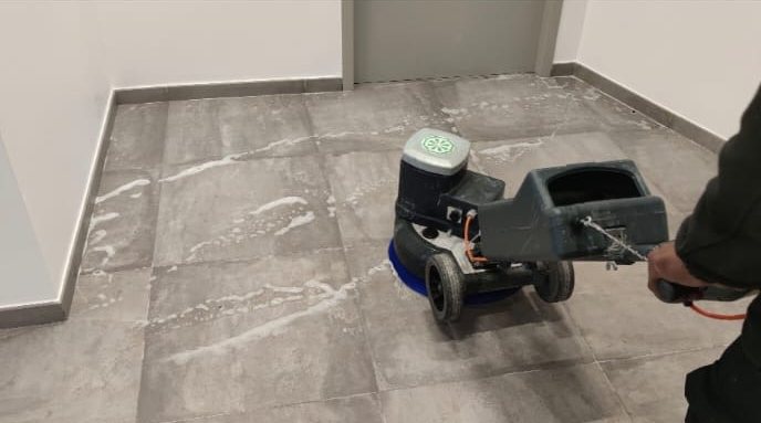 Machine nettoyant un sol en carrelage dans une pièce aux murs blancs